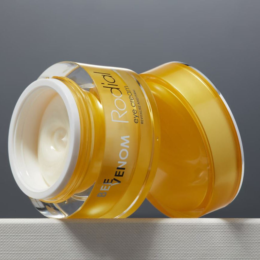 Yellow jar of eye cream with visible brand name on a gray background
