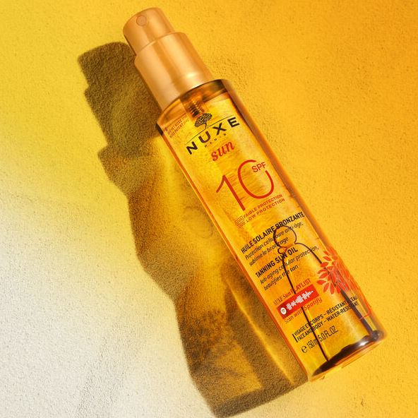 Nuxe sun oil bottle on a yellow background
