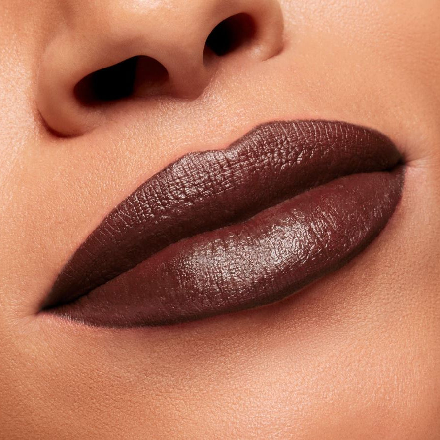 Close-up of a person's lips with dark brown lipstick on a neutral background