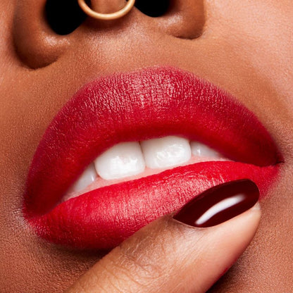 Close-up of a person's lips with red lipstick and a hand holding the lips.