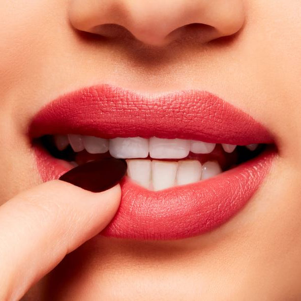 Close-up of a woman's lips with red lipstick and a finger on a neutral background