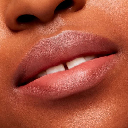 Close-up of a person's lips with a soft pink lipstick on a neutral background