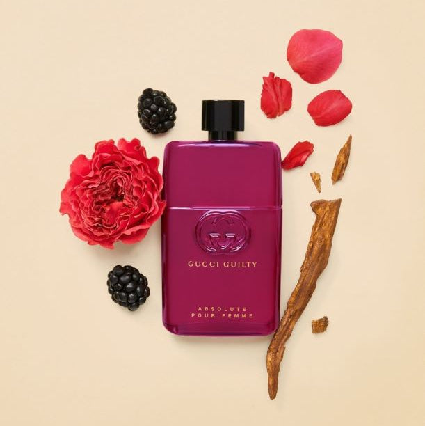 Gucci Guilty Absolute Pour Femme perfume bottle with flowers and blackberries on a beige background