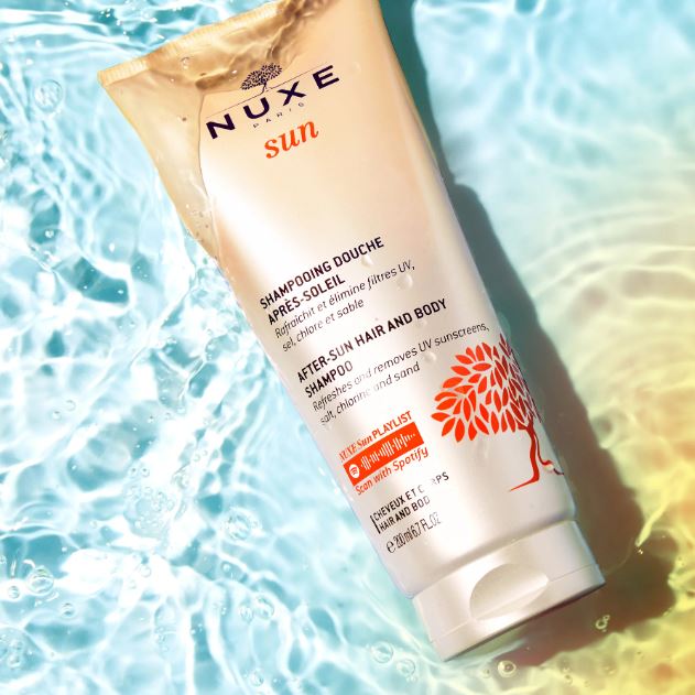 Nuxe sun after-sun hair and body shampoo tube with water background