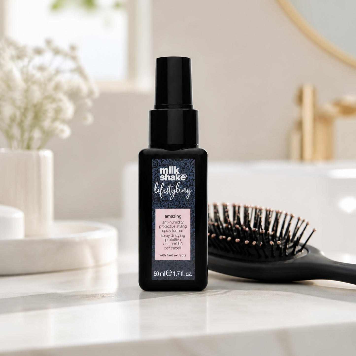 Black hair spray bottle on a bathroom counter with a brush and decorative items in the background