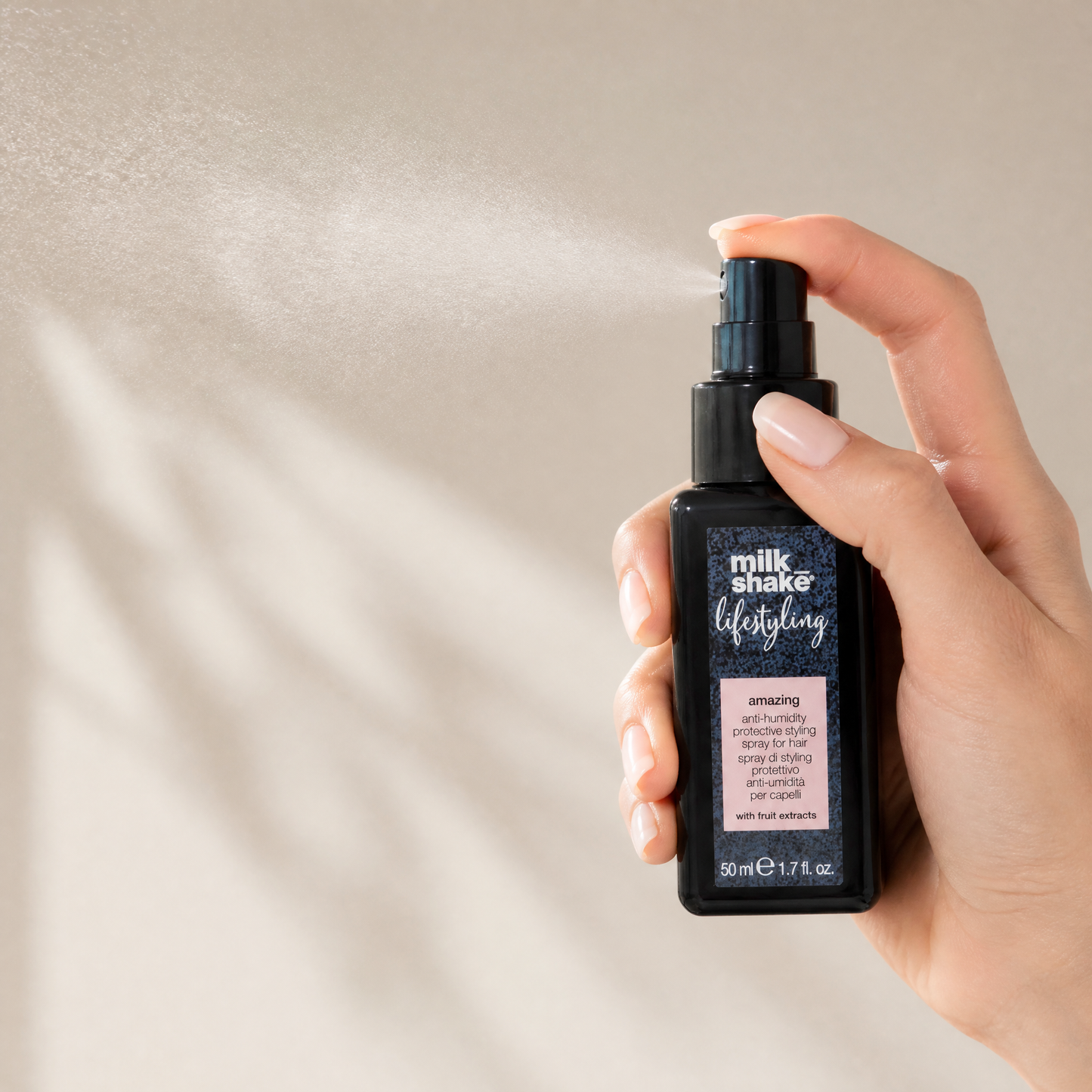 Hand holding a bottle of 'milk shake' hair product against a neutral background