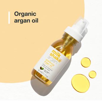 Bottle of organic argan oil with droplets on a beige background