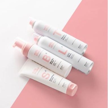Set of white and pink hair care products on a pink and white background