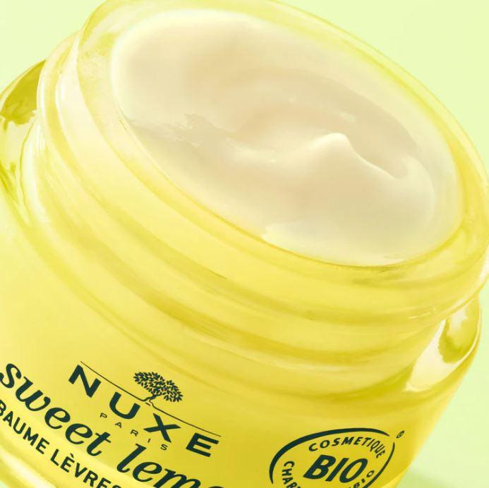Nuxe lip balm jar with cream visible on a light green background