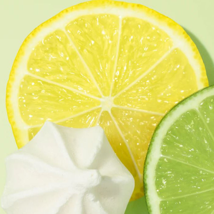 Sliced lemon, lime, and whipped cream on a light green background