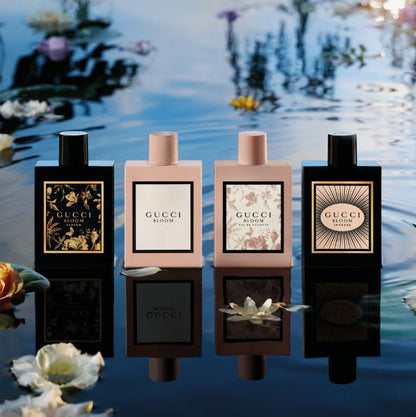 Four Gucci perfume bottles with floral designs on a water background