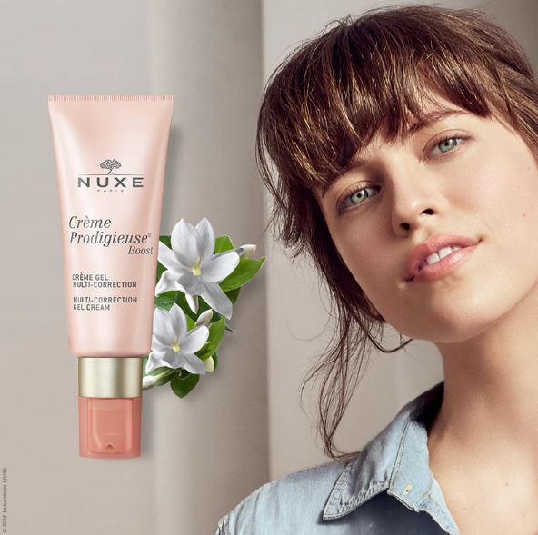Nuxe cream tube with a woman's face on a neutral background