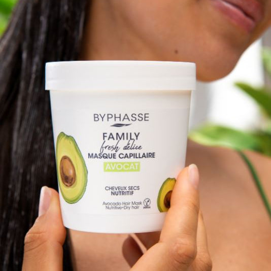 Byphasse avocado hair mask container held by a person with blurred background