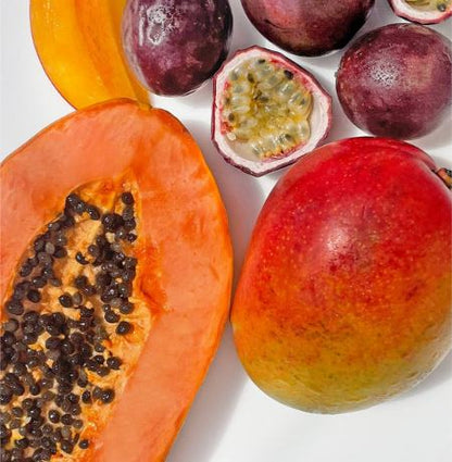 Assorted tropical fruits including a papaya, mango, and passion fruit on a white background