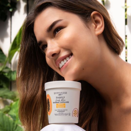 Woman holding a Byphasse hair care product with a natural background