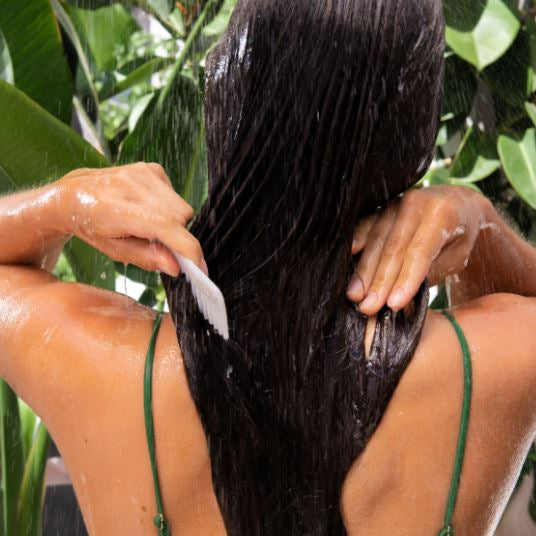 Person washing hair with a brush in a shower setting