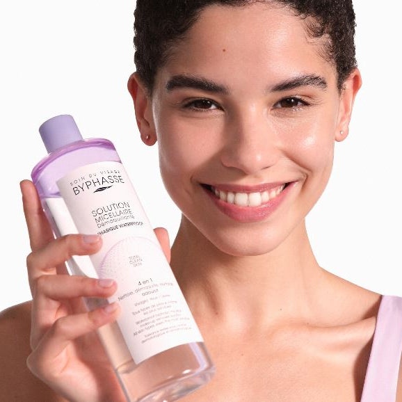 Woman holding a Byphasse micellar water bottle against a white background