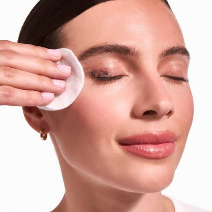 Woman applying a skincare product to her face with a cotton pad.