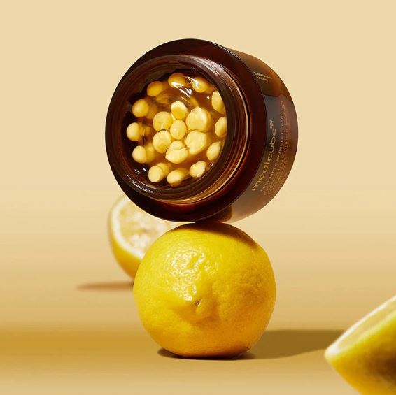 Jar of cosmetic product with lemons on a beige background