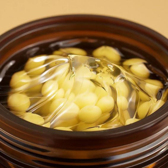 Close-up of a bowl with clear gelatin sheets and yellow spherical objects on a beige background