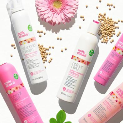 Milk Shake hair care products with pink and white packaging on a light background.