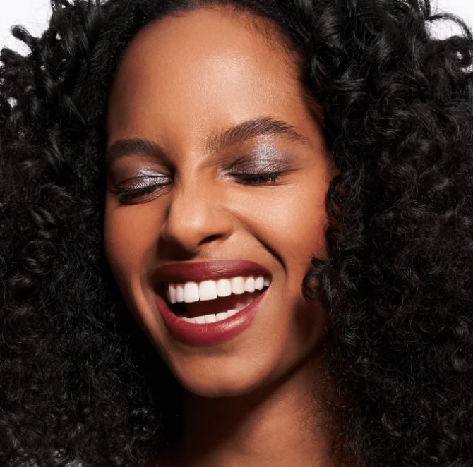 Close-up of a woman with a big smile and curly hair