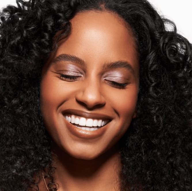 Close-up of a woman with a bright smile and curly hair against a white background