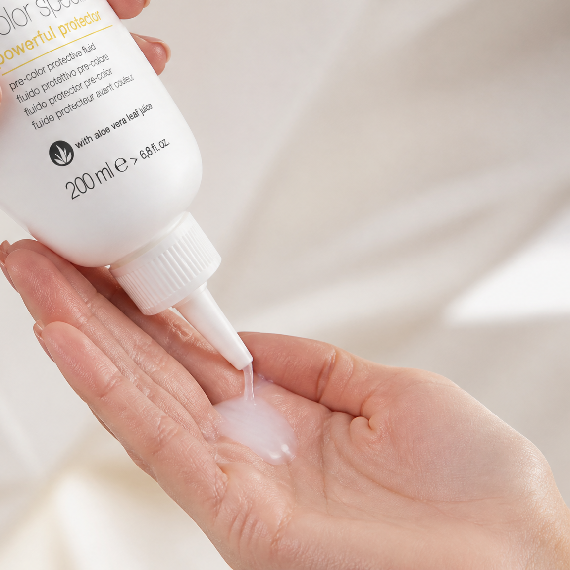 Person applying milk_shake hair color product to a hand against a neutral background