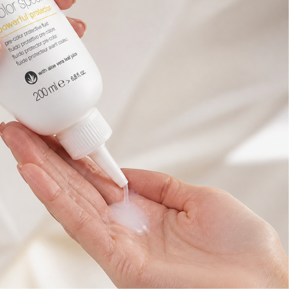 Person applying milk_shake hair color product to a hand against a neutral background