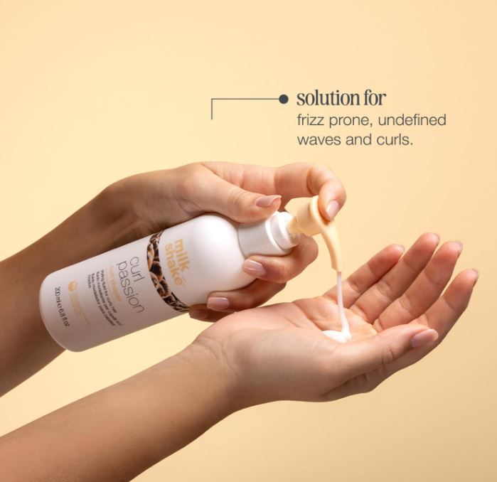 Hand holding a bottle of Zennelle Curl Passion product with a beige background