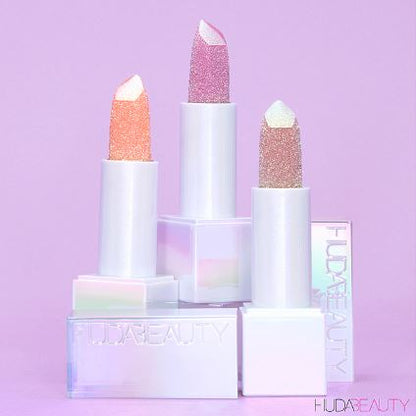 Set of Huda Beauty lipsticks with pastel colors on a purple background
