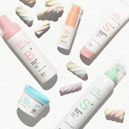 Collection of milk makeup products with colorful marshmallows on a white background