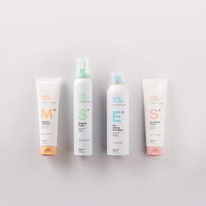 Four bottles of milk makeup products on a light gray background