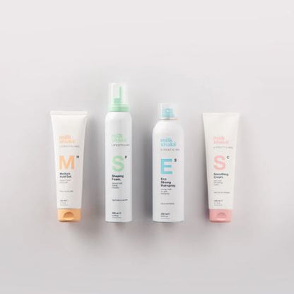 Four bottles of milk makeup products on a light gray background