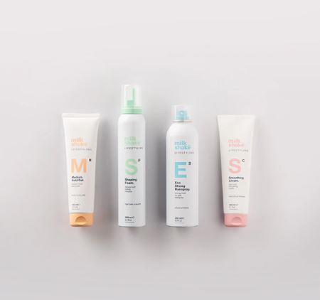 Four bottles of milk makeup products on a light gray background