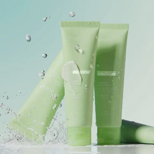 Two green skincare products with water droplets on a light blue background