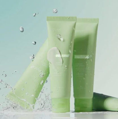 Two green skincare products with water droplets on a light blue background