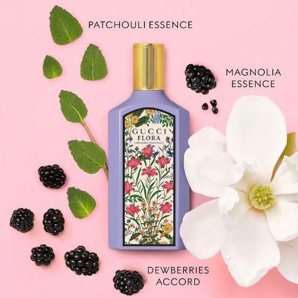 Gucci Flora perfume bottle with floral design on a pink background with blackberries and a white flower.