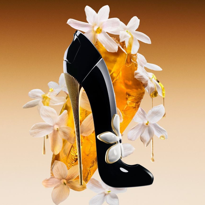 Black high-heeled shoe with gold heel on a background of flowers and a bottle of perfume.