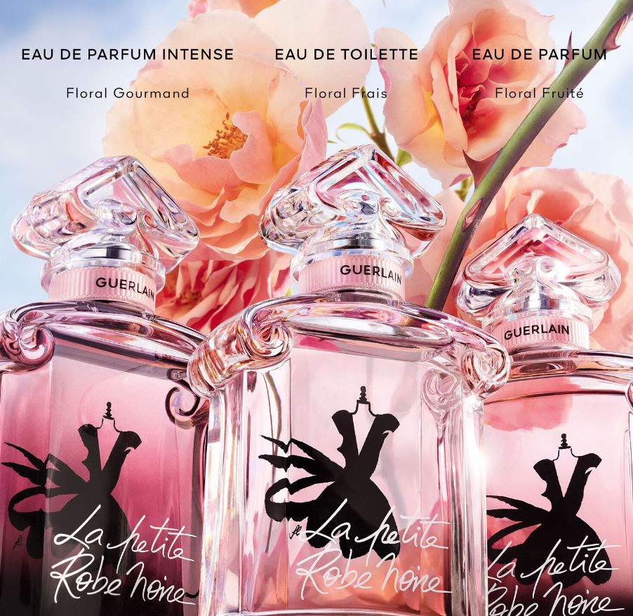 Three Guerlain perfume bottles with floral design and text on a background of pink flowers.