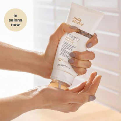 Hand holding a bottle of 'milk snake' integrity product with a blurred background
