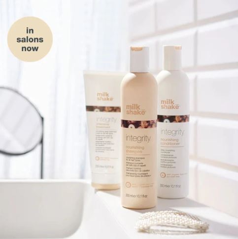 Two bottles of Milk Shake Integrity shampoo and conditioner on a bathroom counter.