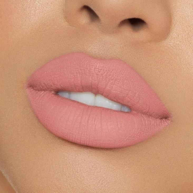 Close-up of a person's lips with pink lipstick on a neutral background
