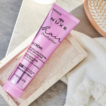 Nuxe hair care product on a textured surface with a brush in the background