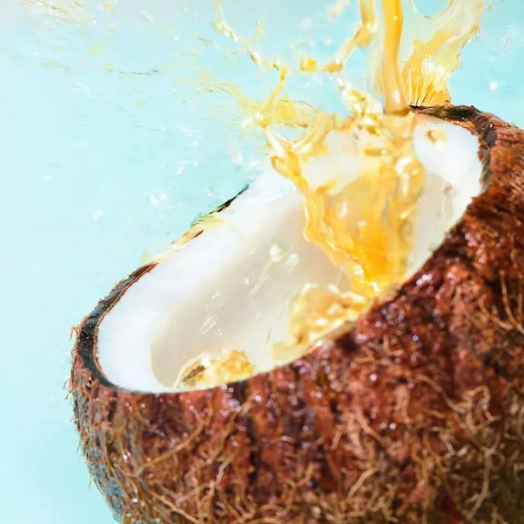 Coconut being poured into a coconut shell against a light blue background