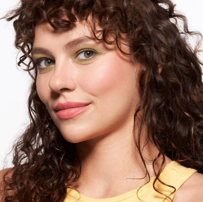 Woman with curly hair wearing a yellow top against a white background