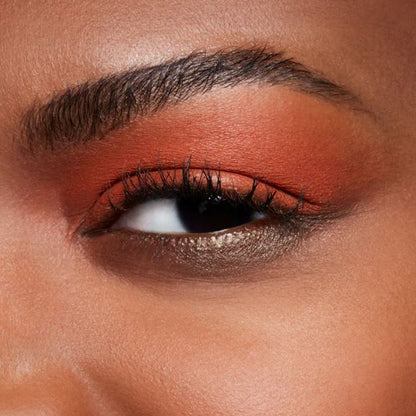 Close-up of a person's eye with orange eyeshadow and long black eyelashes.