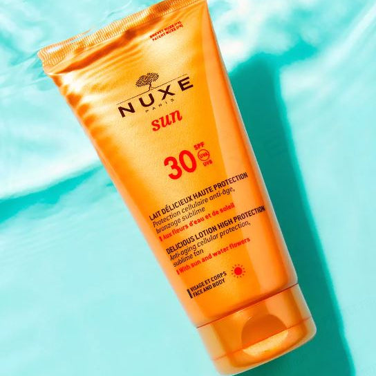 Nuxe sun cream bottle with SPF 30 on a blue background