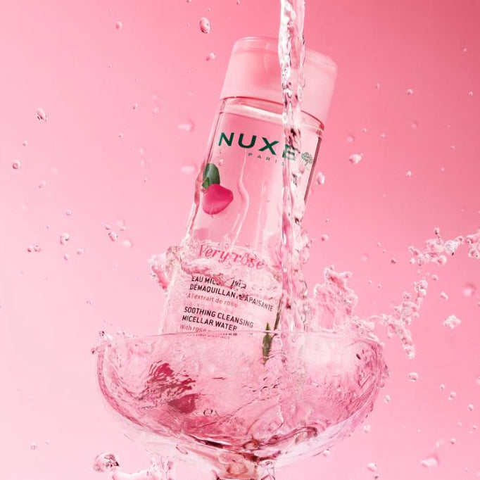 Nuxe skincare product with water splashes on a pink background