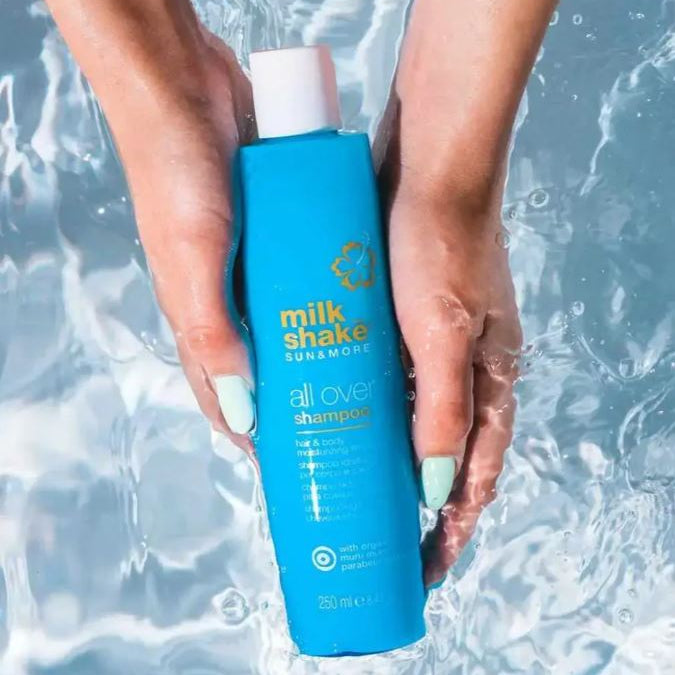Blue shampoo bottle held by hands with water background